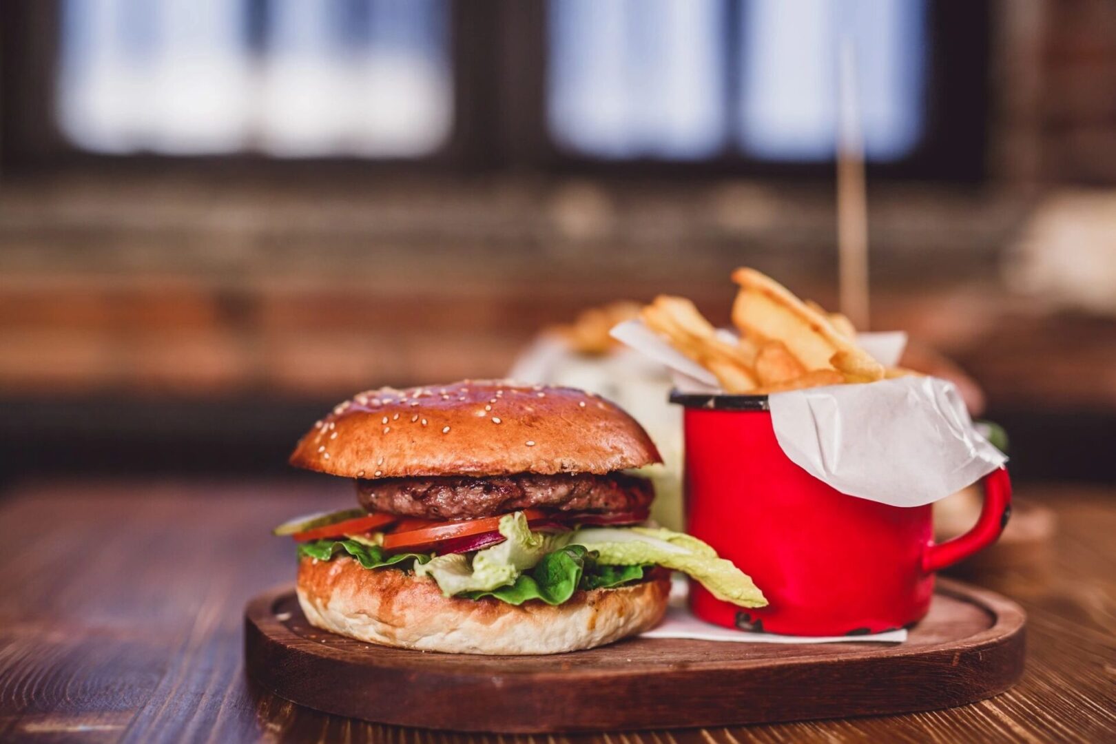 A hamburger and fries on a wooden plate.