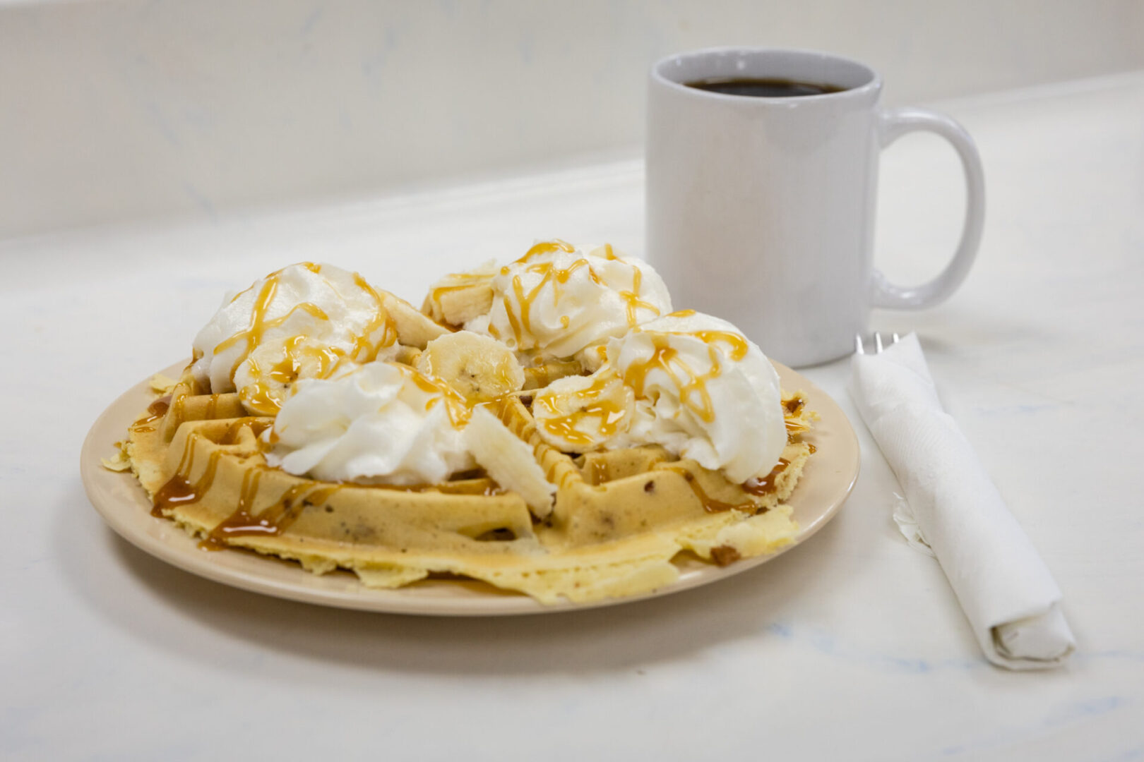 A plate of waffles with whipped cream and caramel.